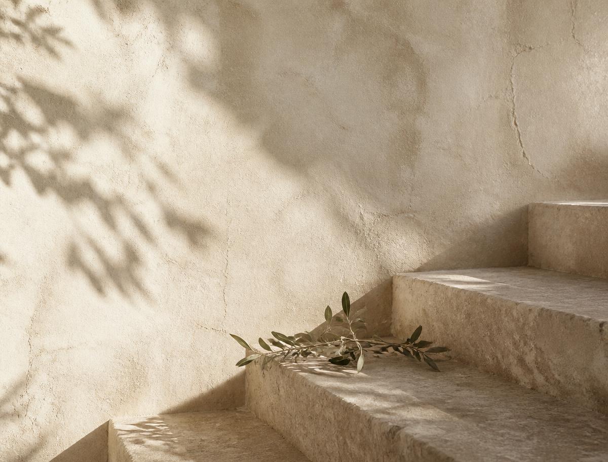 Warm natural plaster walls with soft stone steps and a subtle olive branch.